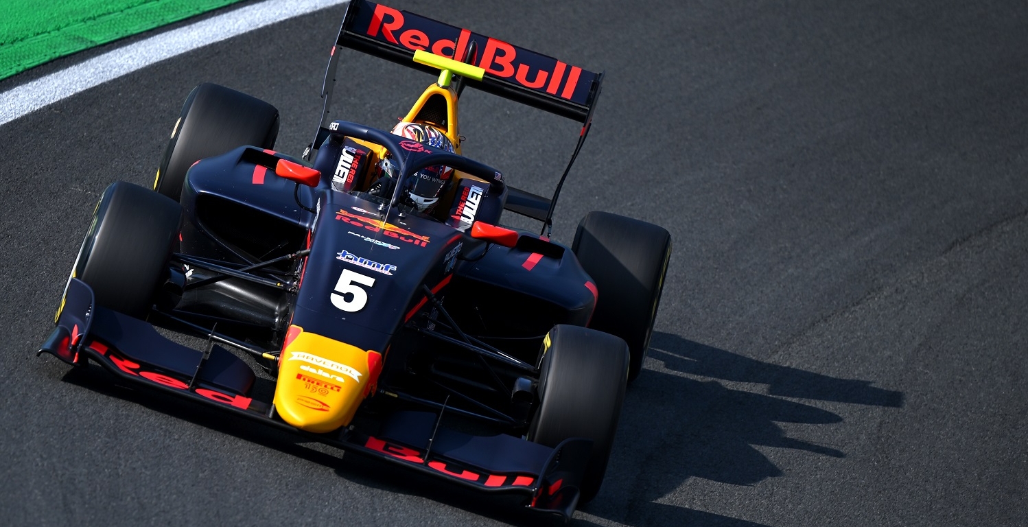 The blue, red and yellow Red Bull–sponsored Prema F3 car of Jak Crawford drives around the banking at the Turn 3 left-hander.