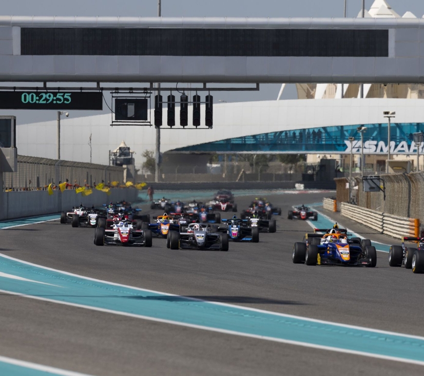 Cars make a slight left on the Yas Marina Circuit along the back straight, with the clock reading 29:55 and the Yas Marina Circuit logo in the background