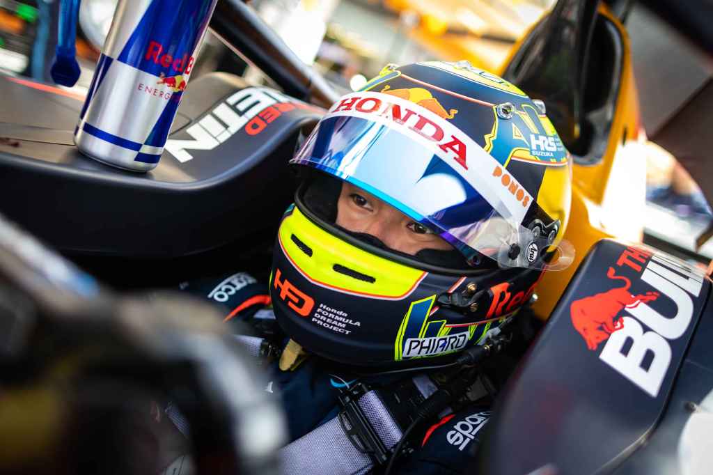 Ayumu Iwasa sits in the cockpit of his Red Bull-branded DAMS FIA Formula 2 car with his helmet on