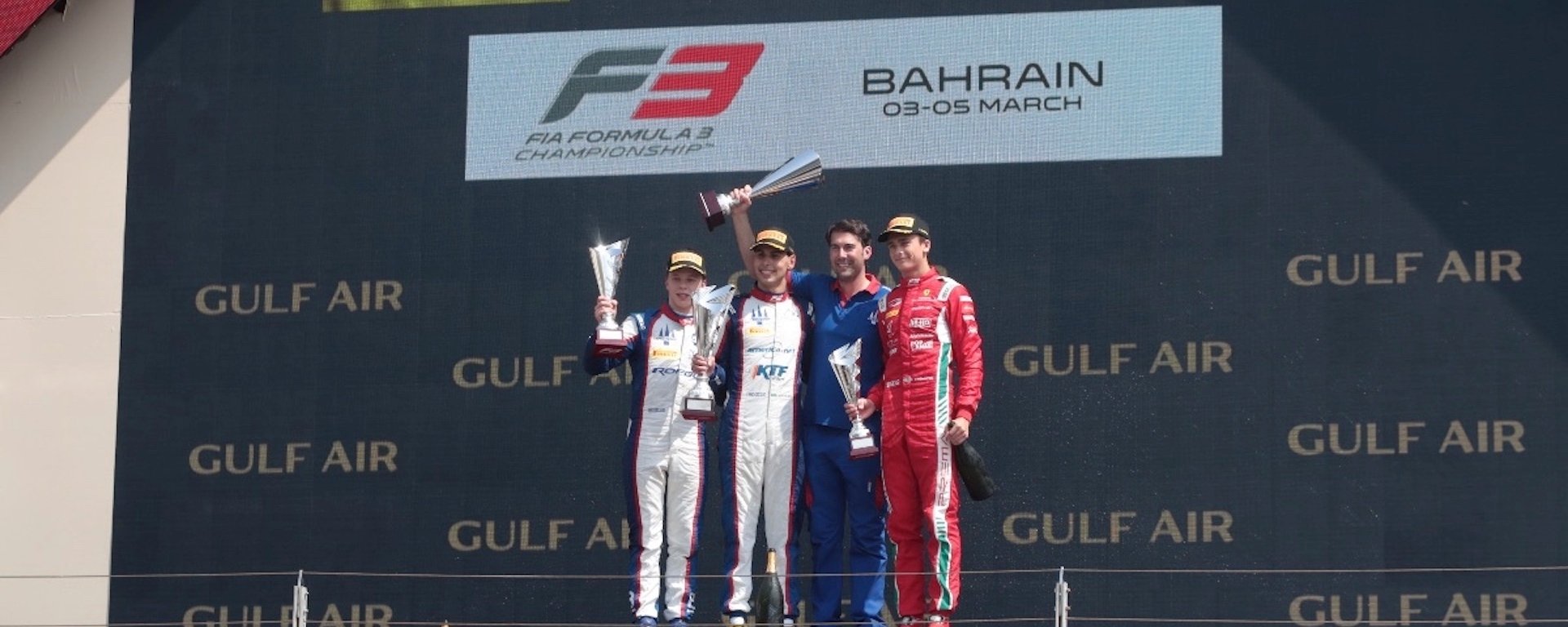 Four men on the #1 step of the podium with the German, Brazilian, and Swedish flags in the background and the text "FIA Formula 3 Championship Bahrain 03–05 March" displayed in the background above Gulf Air sponsorship.